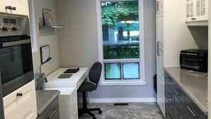 A modern kitchen with a built-in oven, a countertop with a toaster, and a window with a view of greenery outside. - TO Stays - Waterfront Lake House Retreat (Ryerson)