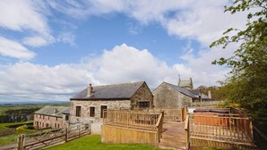 A stone farmhouse with a wooden deck and a fenced yard. - Mill Barn (Hot Tub) 2 bedrooms (Brampton)