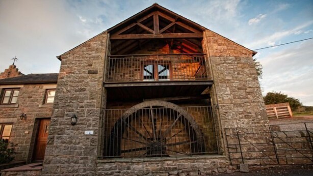 A stone building with a wooden balcony and a large arched window. - Mill Barn (Hot Tub) 2 bedrooms (Brampton)