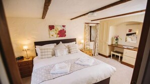 A bedroom with a large bed, a nightstand, a dresser, and a mirror. - Mill Barn (Hot Tub) 2 bedrooms (Brampton)
