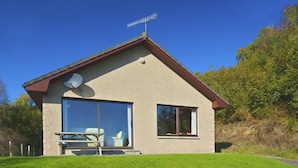 A modern house with a satellite dish, large windows, and a picnic table. - Achmony Green lodge (Inverness)