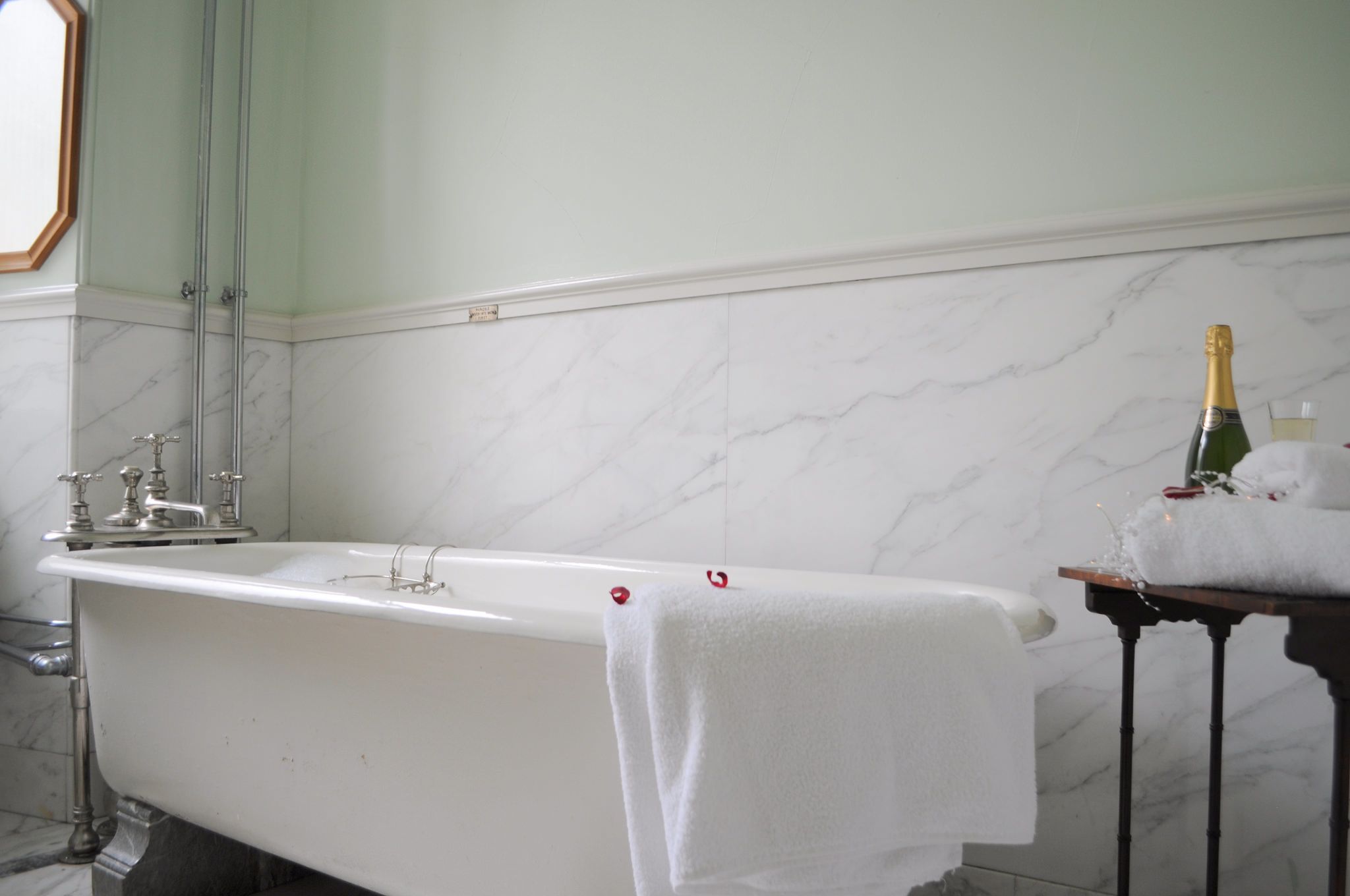 A bathroom with a bathtub, a towel, and a bottle of champagne.