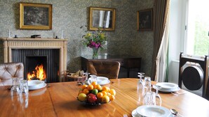 Una sala da pranzo con camino, un tavolo imbandito per quattro persone e un vaso con fiori.