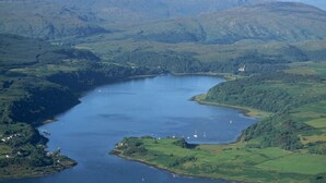 Un lago circondato da dolci colline e montagne verdi.