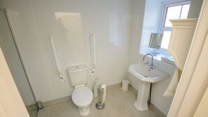 Une petite salle de bain propre, équipée de toilettes, d’un lavabo et d’un miroir.