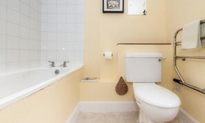 A small bathroom with a white bathtub, a toilet, and a towel rack. - Kennels (Isle of Colonsay)