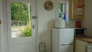 A compact kitchen with a refrigerator, microwave, and a small window.