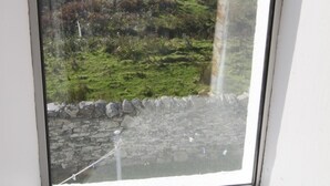 A window with a view of a green landscape and hills. - Garvard (Isle of Colonsay)