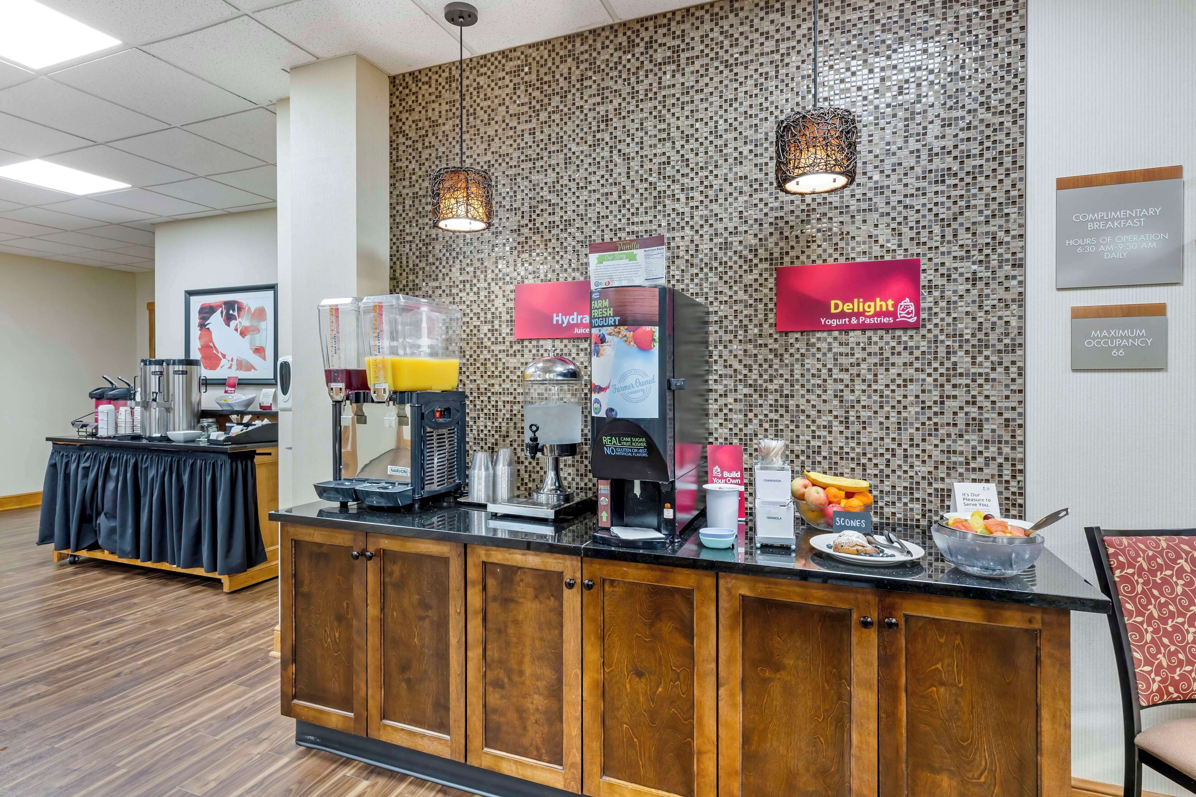 A breakfast bar with a coffee machine, juice dispenser, and various food items.