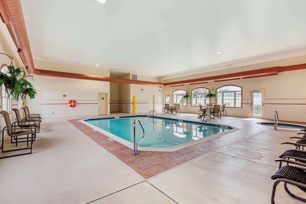 An indoor swimming pool with a tiled floor, lounge chairs, and a table with chairs. - Best Western Plus Dutch Haus Inn and Suites (Columbiana)