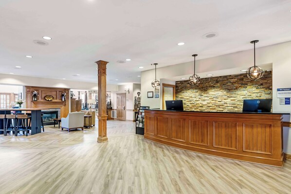 A spacious lobby with a wooden reception desk, a stone accent wall, and a fireplace. - Best Western Plus Dutch Haus Inn and Suites (Columbiana)