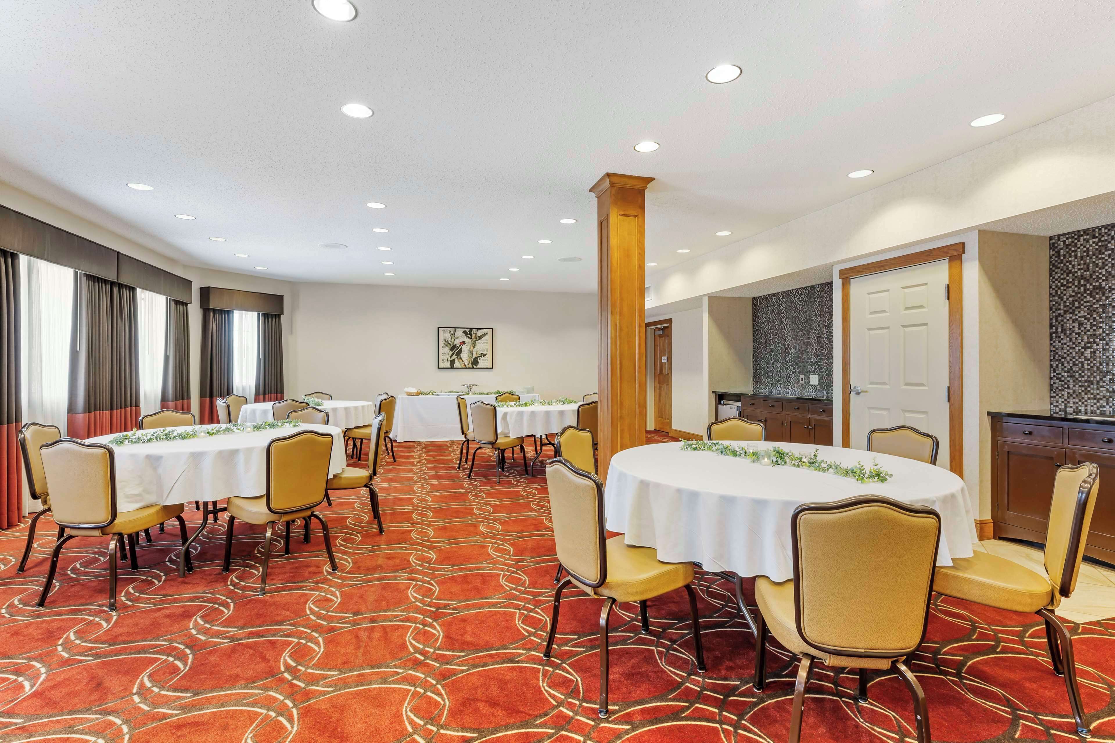 A conference room with round tables and chairs, a patterned carpet, and a large pillar.