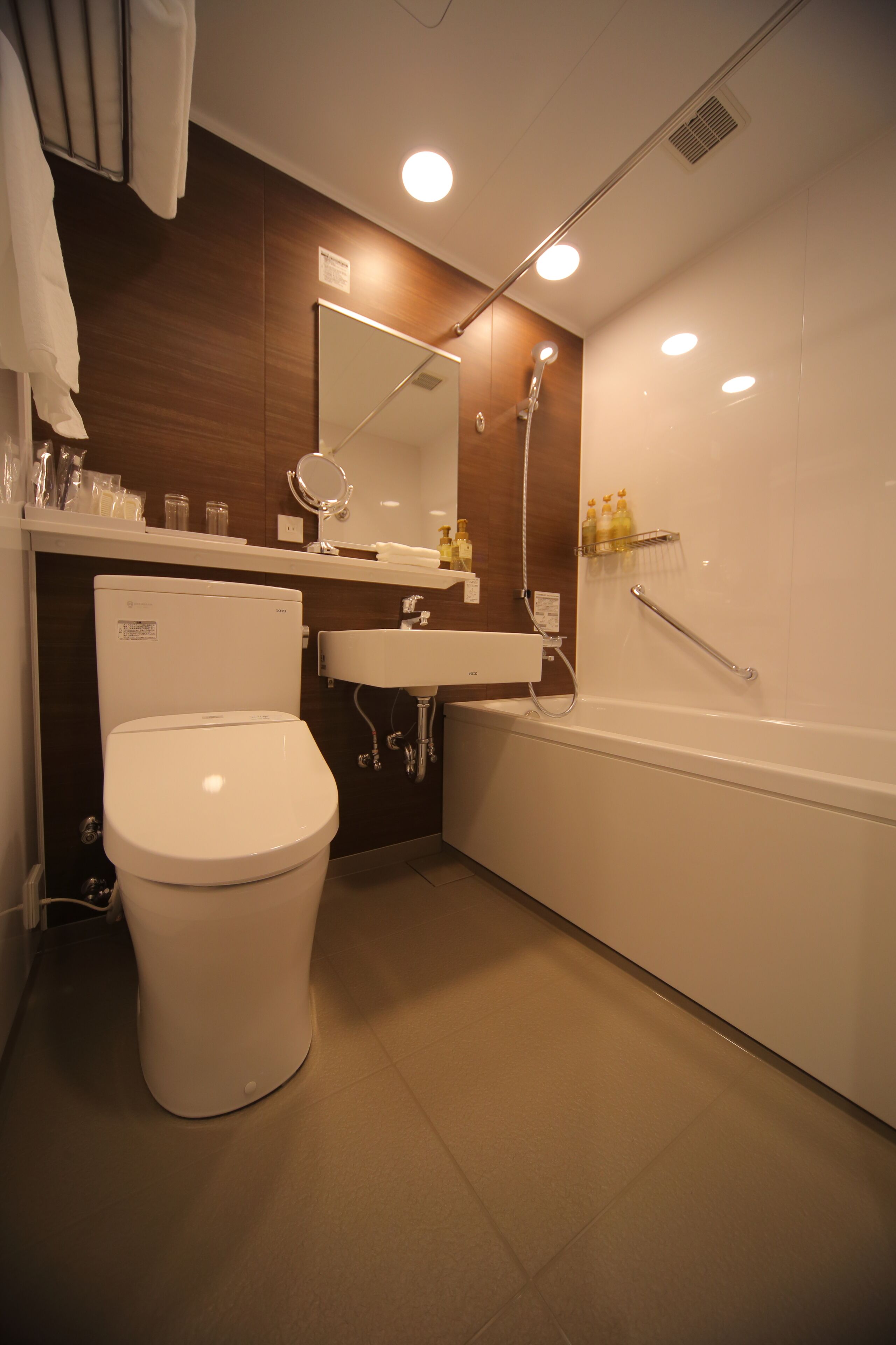A modern bathroom with a toilet, sink, mirror, and shower.