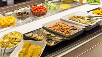 Un bufé con diversos alimentos, entre ellos frutas, verduras y platos cocinados.