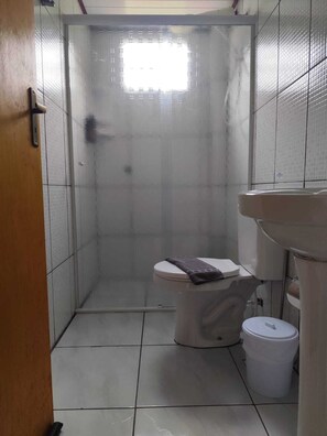 A bathroom with a toilet, a sink, and a shower enclosure.