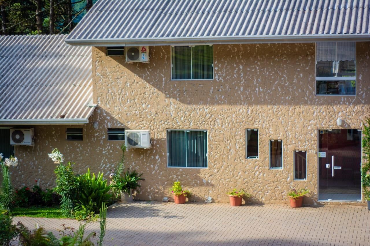 A building with a corrugated metal roof, air conditioning units, and potted plants in front.