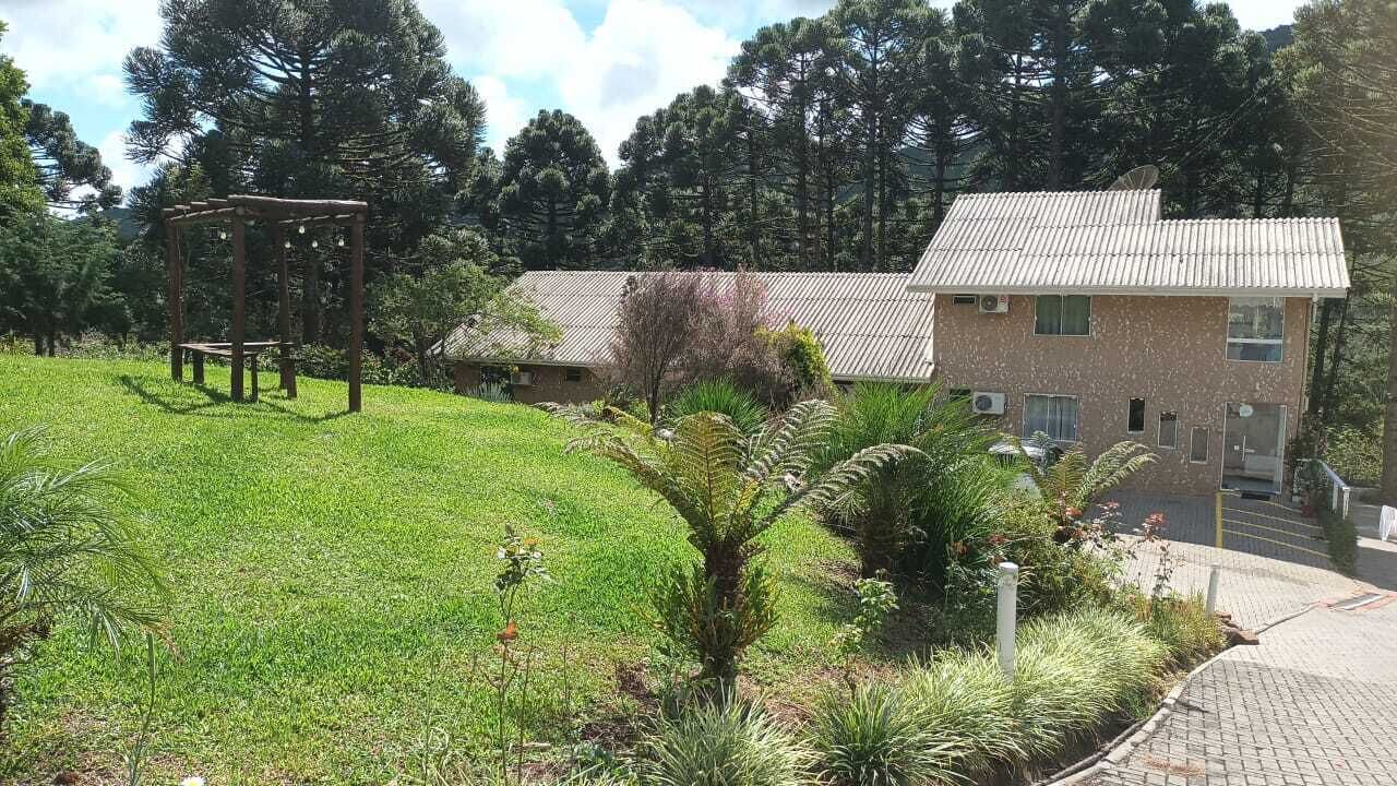 Un edificio con techo de tejas, un jardín con pérgola de madera y un sendero pavimentado.