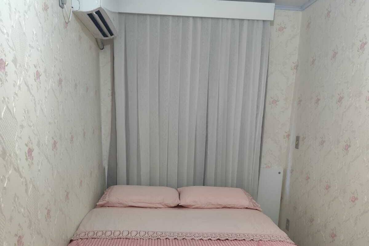 Un dormitorio con cama, ventana con cortinas y un equipo de aire acondicionado.