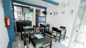 A hotel room with a glass table, chairs, a fire extinguisher, and a poster on the wall. - Hotel Sol de Piura (Piura)