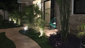 A modern building with a curved pathway, outdoor seating, and lush greenery. - Yaax Kiin (Tulum)