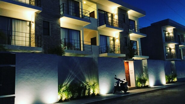 A multi-story building with balconies, a motorcycle parked in front, and a well-lit entrance. - Yaax Kiin (Tulum)