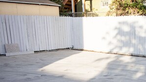 A concrete patio area with a white picket fence. - Los Angeles Extended Stay Hostel (Los Angeles)
