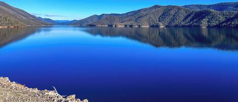 Un lago tranquilo con colinas boscosas al fondo.