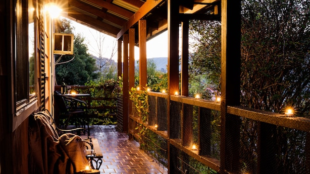 A covered outdoor area with a wooden bench, a table, and string lights. - Pether Cottage - Talbingo NSW (Talbingo)