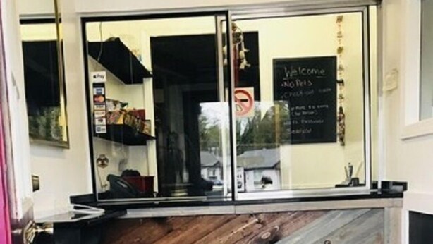 Un espace d’accueil avec un comptoir en bois, une porte vitrée et un panneau d’accueil.