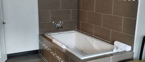 A bathroom with a freestanding bathtub, tiled walls, and a wooden floor.