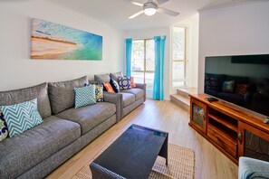 A living room with a sofa, television, and a painting on the wall.