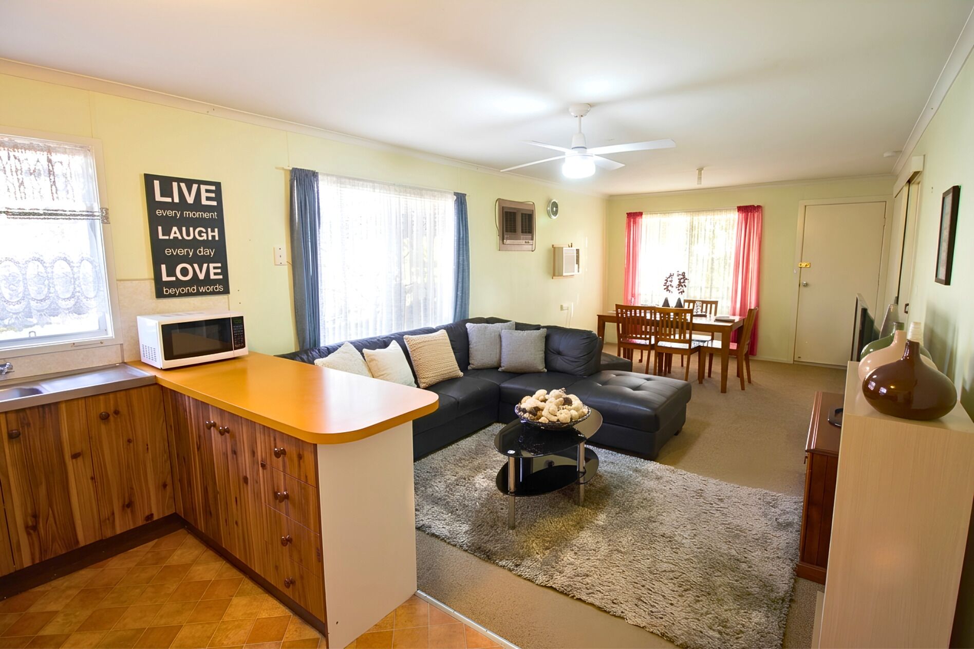 A living room with a sofa, a dining table, and a kitchen area with a microwave.