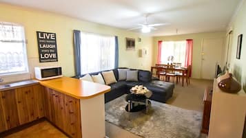 A living room with a sofa, a dining table, and a kitchen area with a microwave.