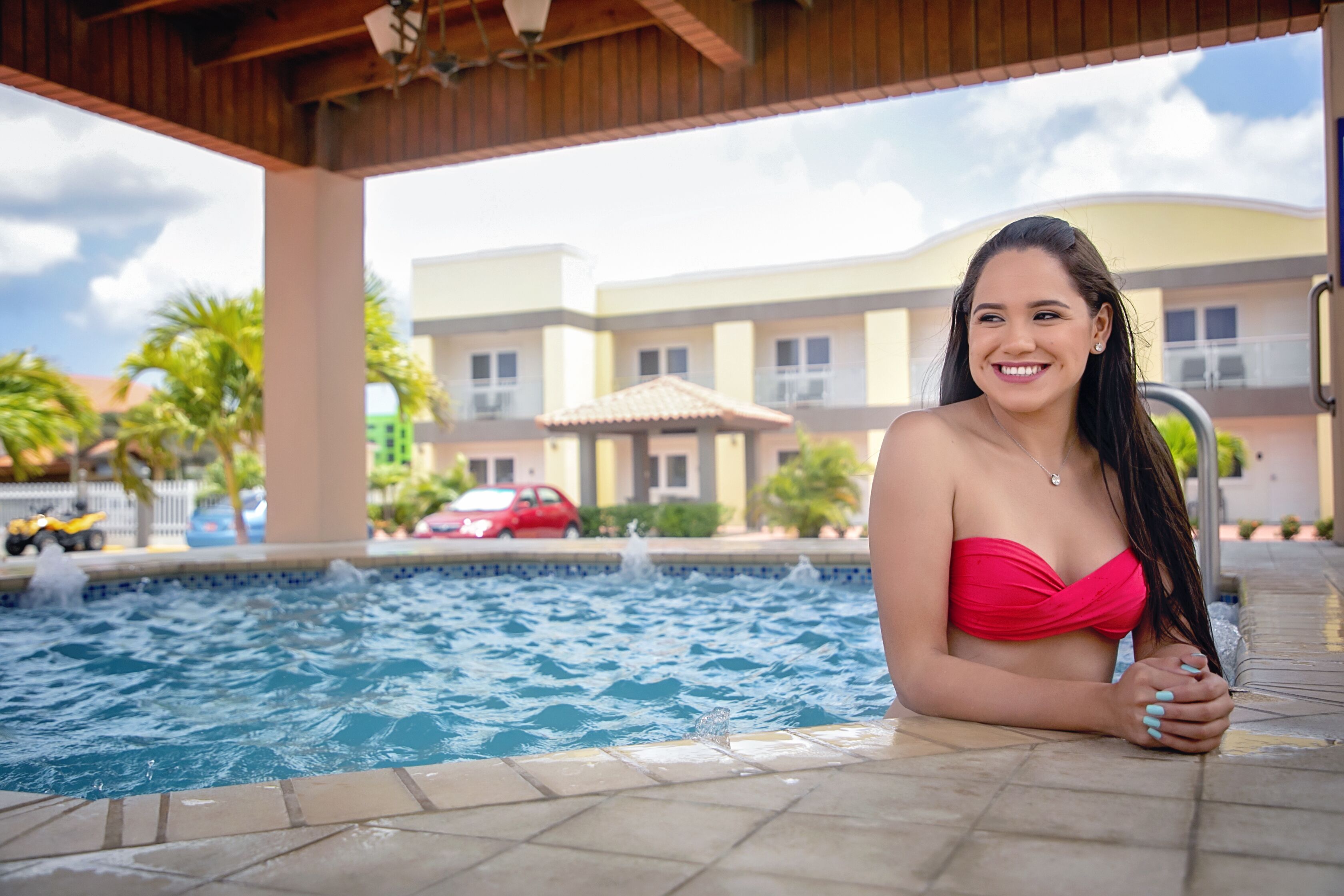 Une personne assise au bord d’une piscine, avec un bâtiment en arrière-plan.