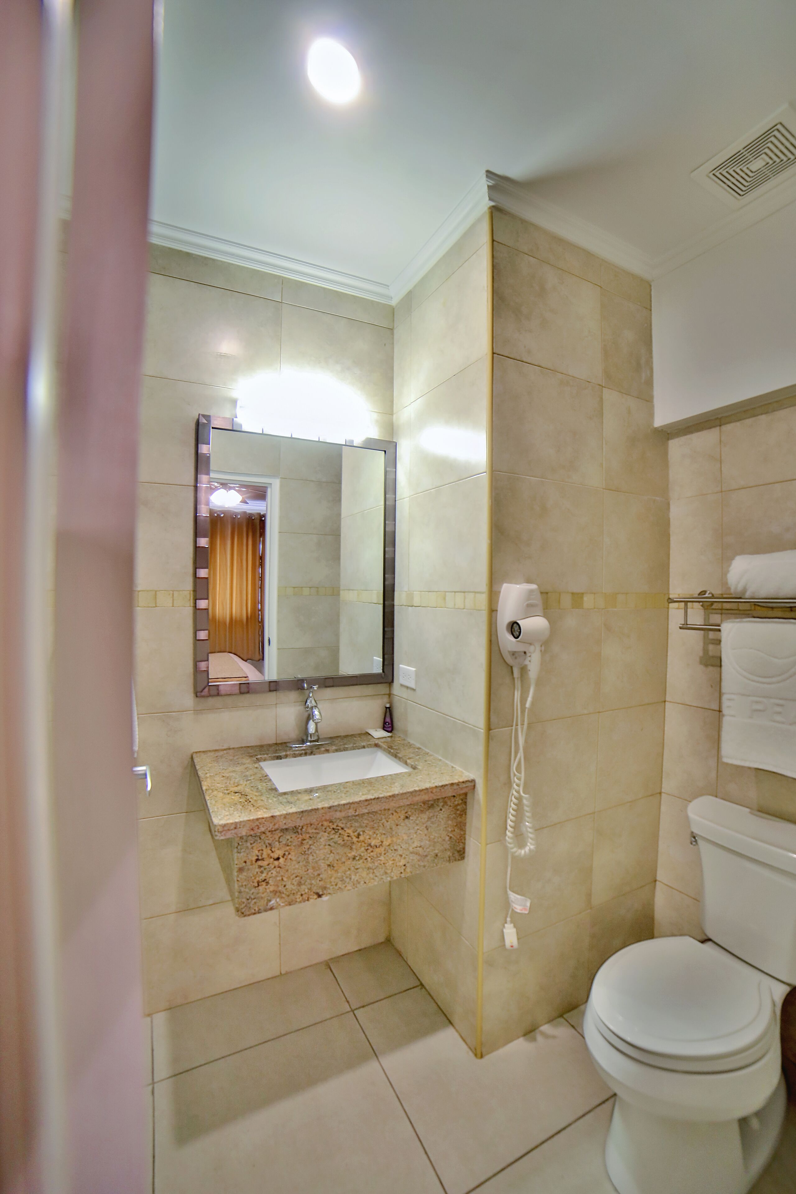 A bathroom with a sink, mirror, toilet, and towel rack.
