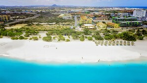 Vista aérea de una zona costera con playa, carretera y edificios.