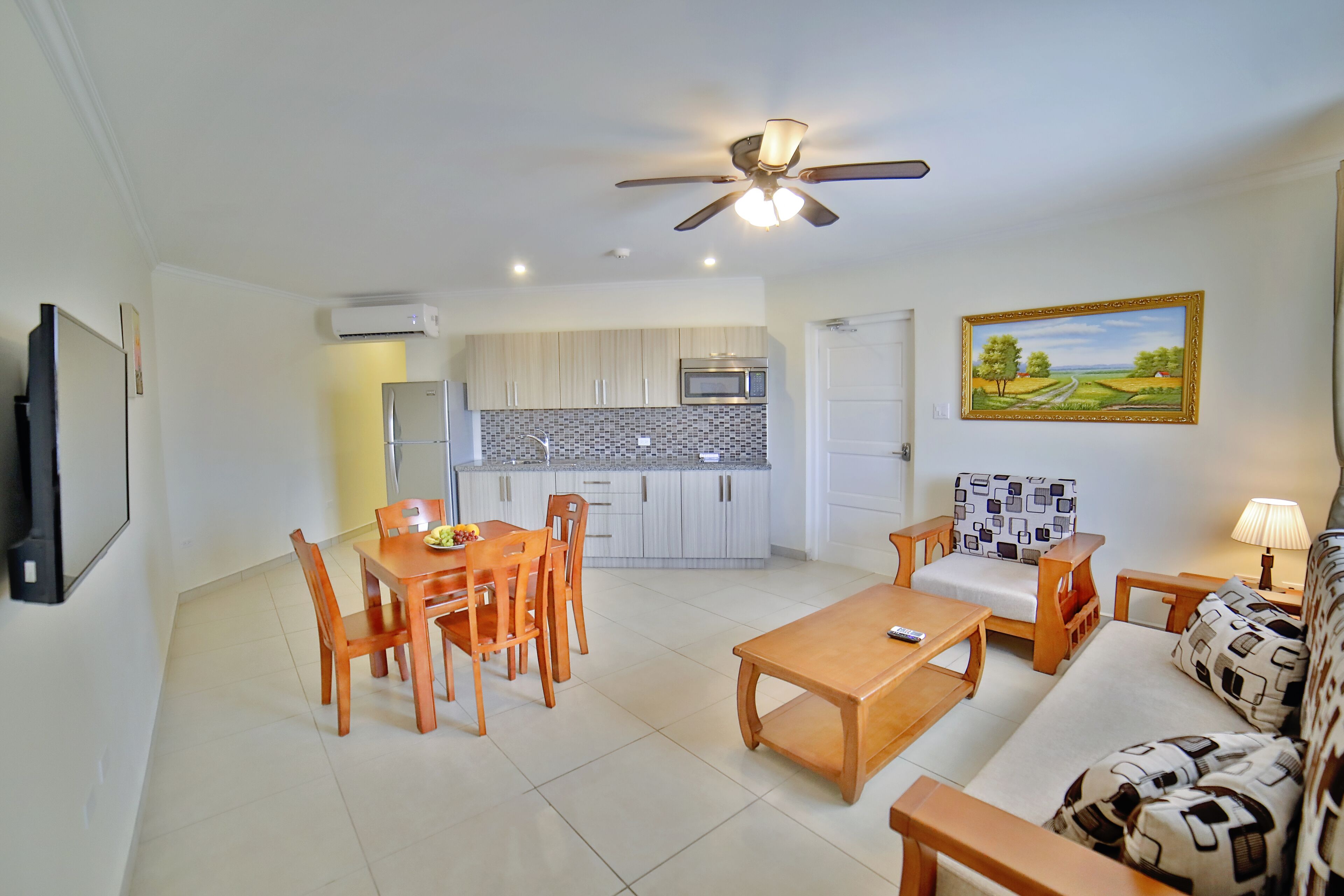 A modern living room with a dining area, kitchen, and a ceiling fan.