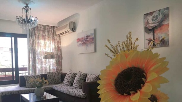 A living room with a sofa, a coffee table, and a large sunflower decoration. - Heliopolis Apartment (Cairo)