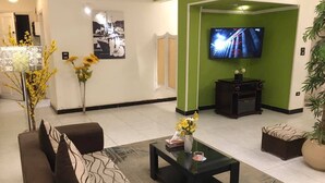 A modern living room with a sofa, coffee table, and a TV on a green wall. - Heliopolis Apartment (Cairo)