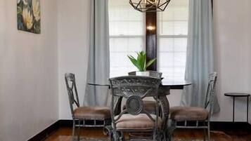 Un coin repas comprenant une table ronde, quatre chaises, un luminaire suspendu et un tapis à motifs.