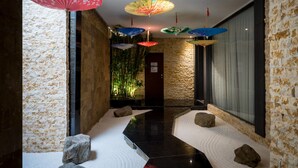 A corridor with a stone wall on one side, a wooden wall on the other, and a floor with white sand and rocks. - Shu Shia Motel (Taichung)