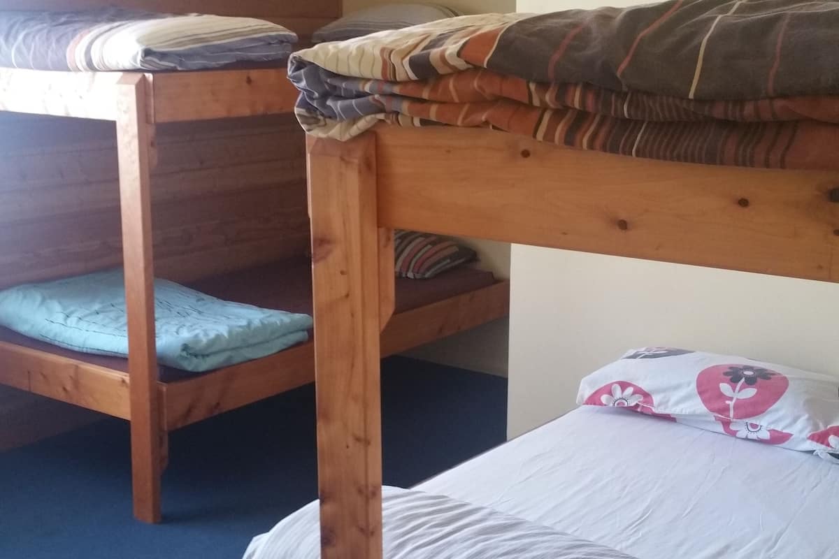 Ein Etagenbett mit Holzgestell und einer Matratze, versehen mit einem gestreiften Kopfkissen.
