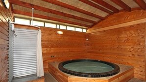 Een houten chalet met een jacuzzi, een douchegedeelte en een raam voor natuurlijk licht.