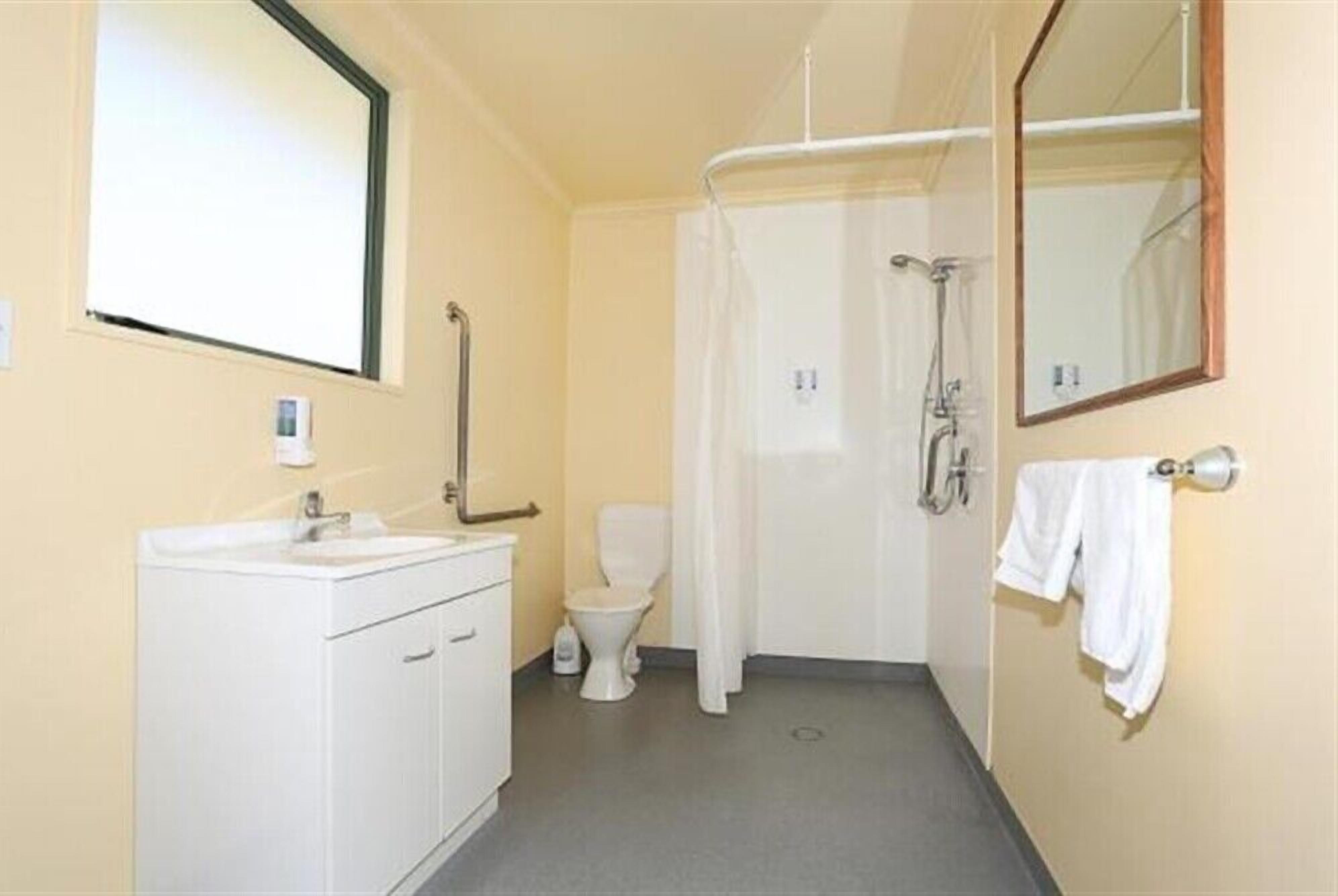 A small bathroom with a toilet, sink, and shower.