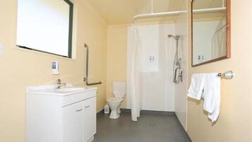 A small bathroom with a toilet, sink, and shower.