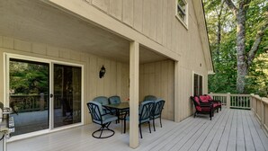 Une terrasse couverte avec une table et des chaises, une porte-fenêtre coulissante et un petit espace de détente extérieur.