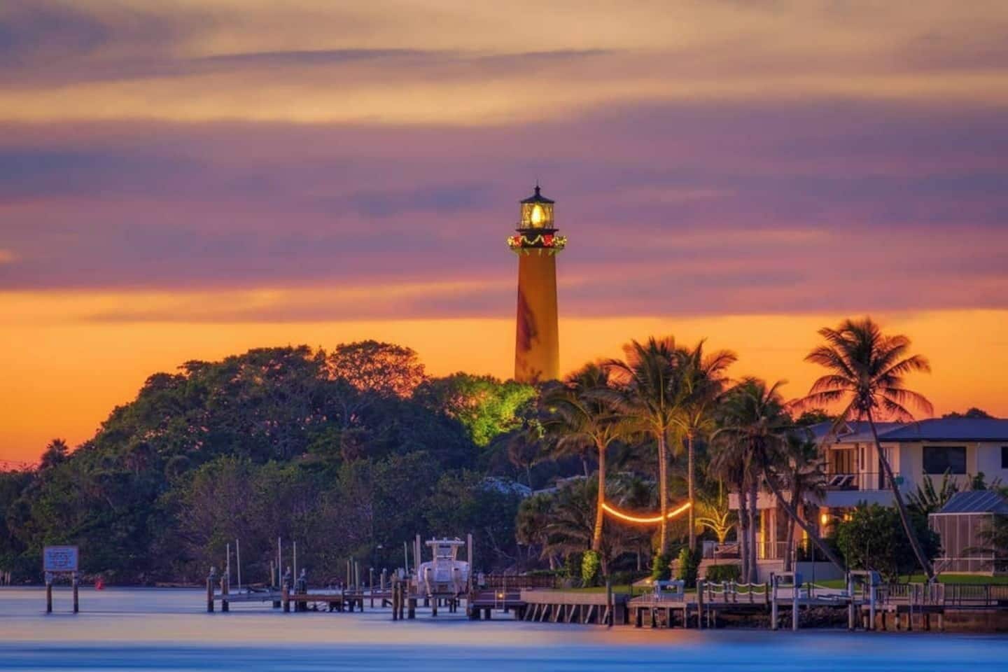 A lighthouse at sunset with a view of the surrounding landscape and a dock area.