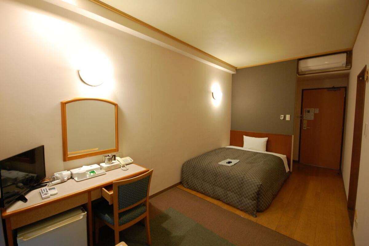 Une chambre d’hôtel équipée d’un lit, d’un bureau, d’une chaise et d’un téléviseur.