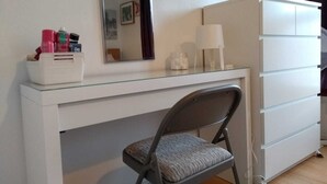Een witte bureau met spiegel, een stoel en een kapstok.