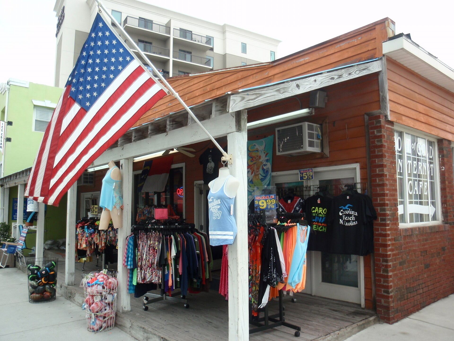A storefront with an American flag, mannequins, and various clothing items on display.